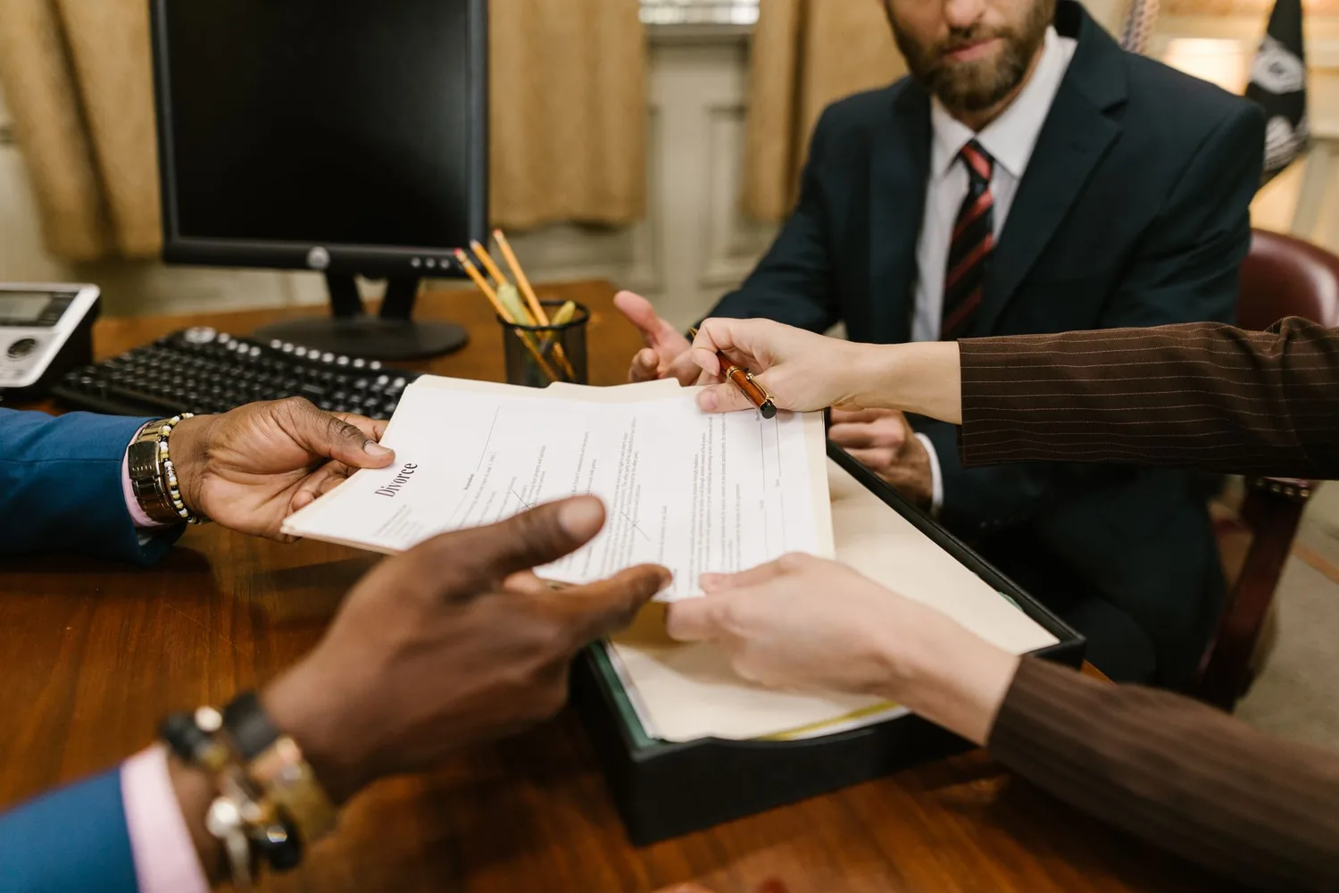 Duas pessoas conversando em uma mesa de escritório com contrato aberto entre elas