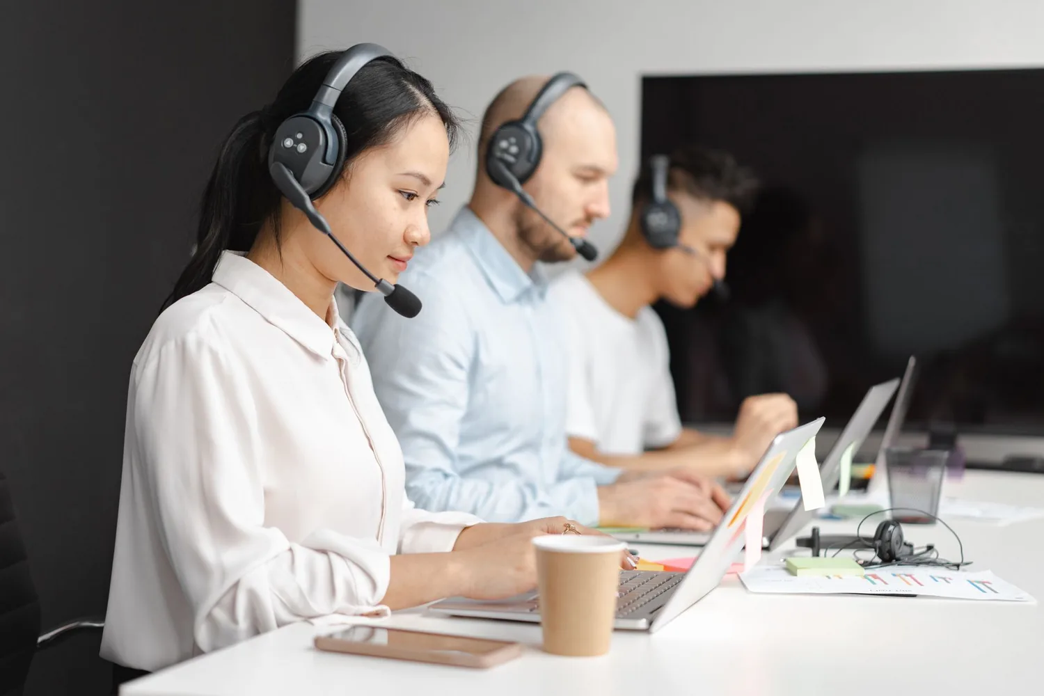 Atendente com headset trabalhando em computador em um escritório de suporte