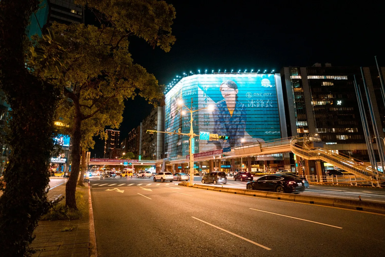 Painéis publicitários iluminados em rua movimentada da cidade ao anoitecer
