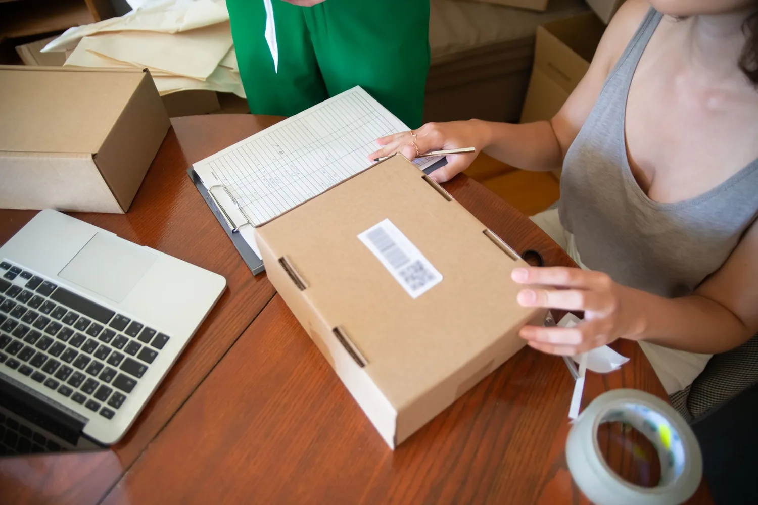 Pessoa organizando pedidos e caixas de encomenda em um pequeno negócio