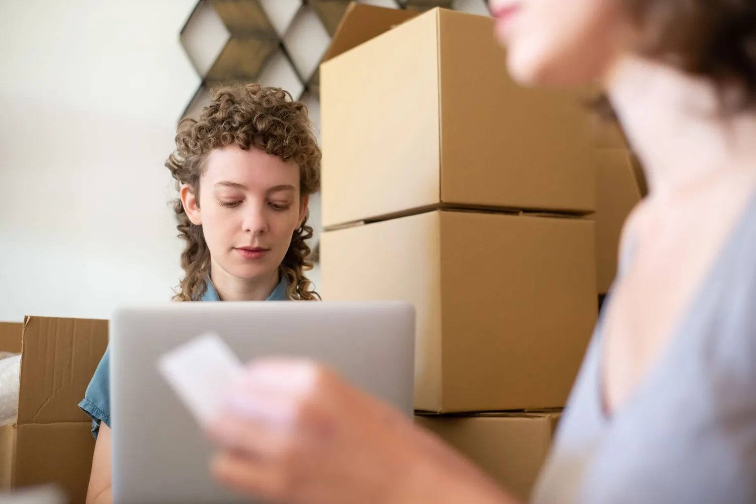 Notebook com painel de vendas online e planilha de pedidos ao lado de caixas